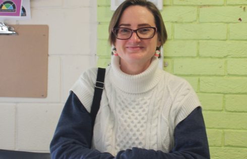 A woman with short brown hair in a white knitted jumper stood smiling