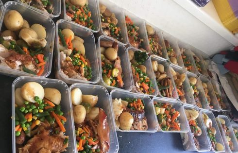 A table with many rectangular tuppaware boxes full of food